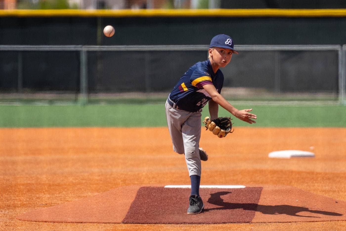Youth baseball pitcher delivering a pitch during game action